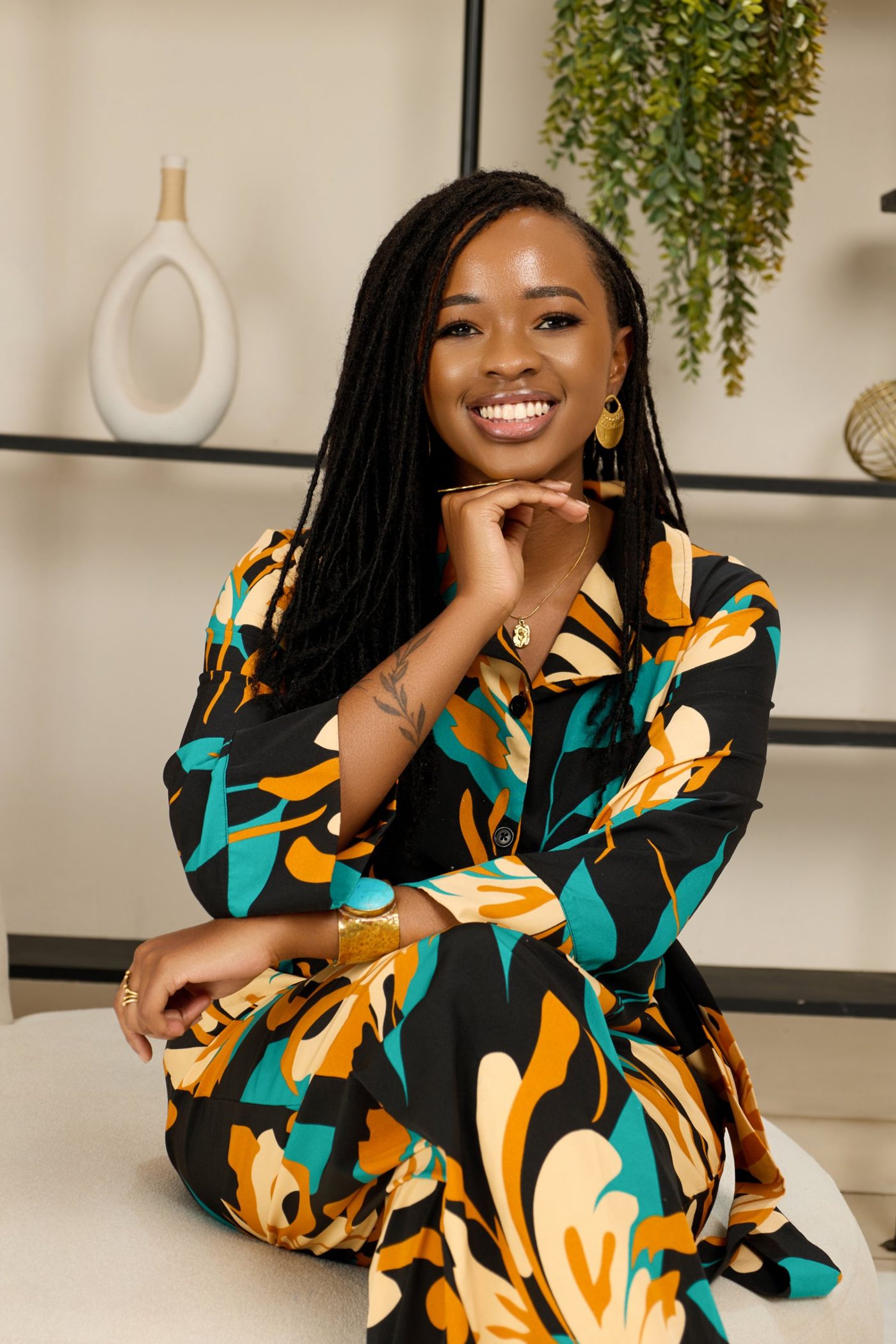 Esther Ndung'u smiling, wearing a black, teal and marigold printed outfit